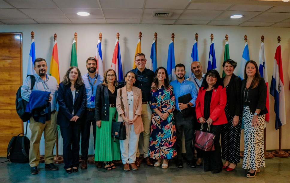 Participantes en un evento internacional con banderas de diferentes países.