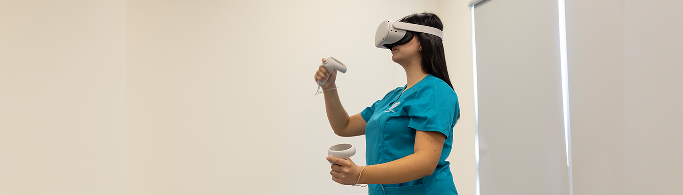 Estudiante de Ciencias de la Salud UC usa visor de realidad virtual y controles en sesión de simulación clínica